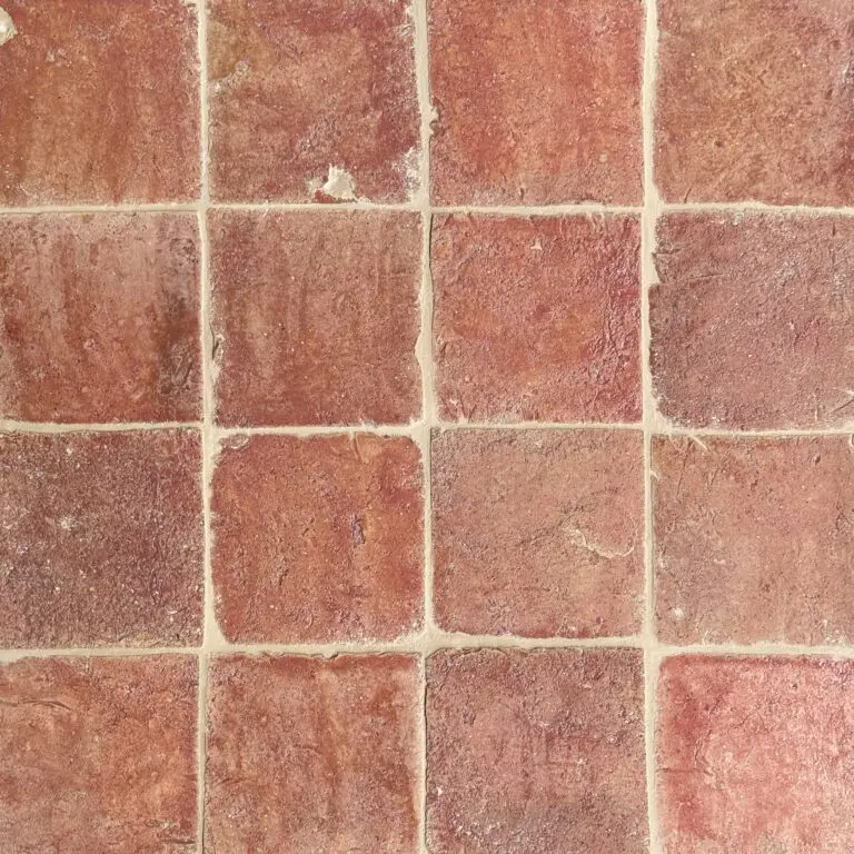 närbild av ett glaserat tegelgolv med röd/rosa nyanser som skapar en livfull atmosfär.