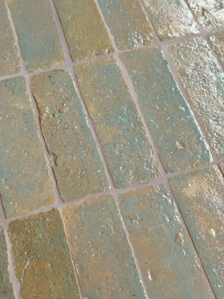 närbild av ett glaserat tegelgolv med turkosa nyanser som skapar en livfull atmosfär.