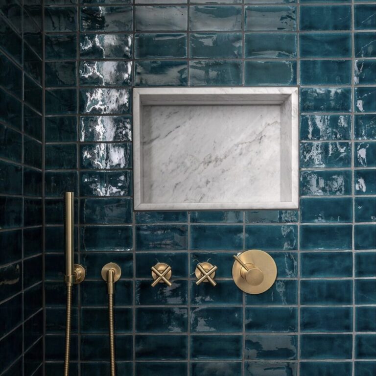 dusch med mörkblått handgjort kakel på vägg och hylla av marmor