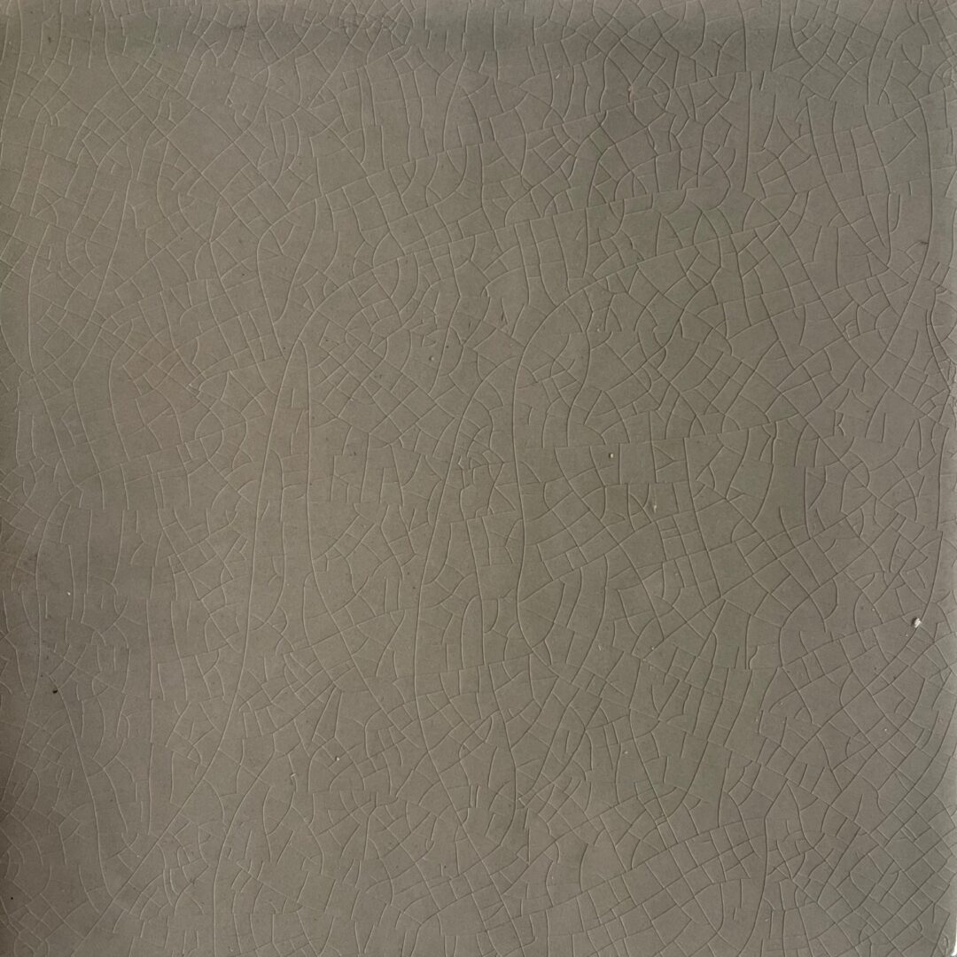 Närbild på en grå/grön krackelerad kakelplatta