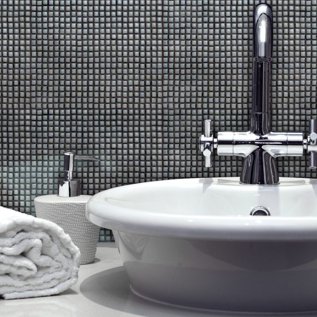 badrum med grå keramikmosaik i form av små kvadrater på väggen