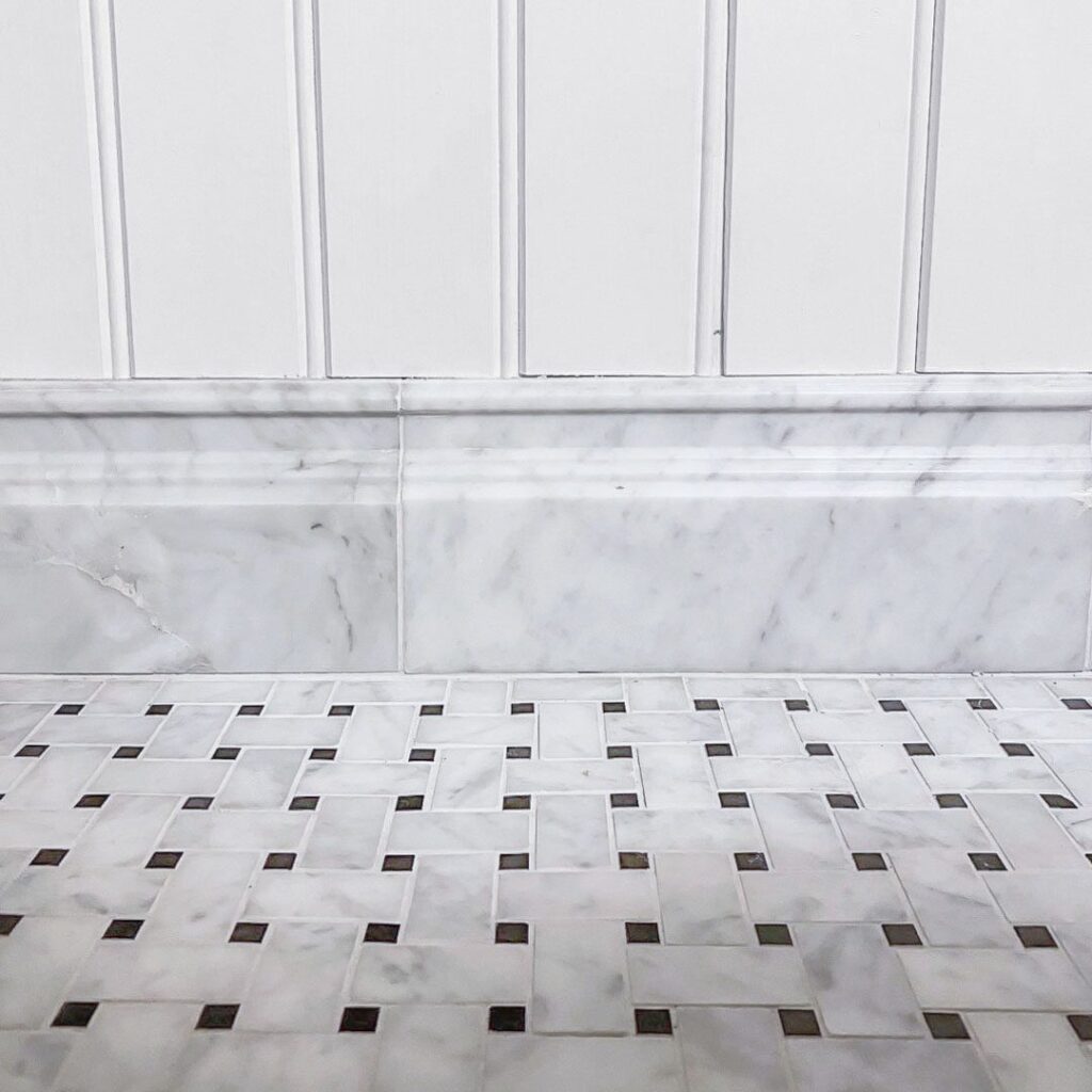 golvlist i carrara med marmormosaik i flätmönster på golvet