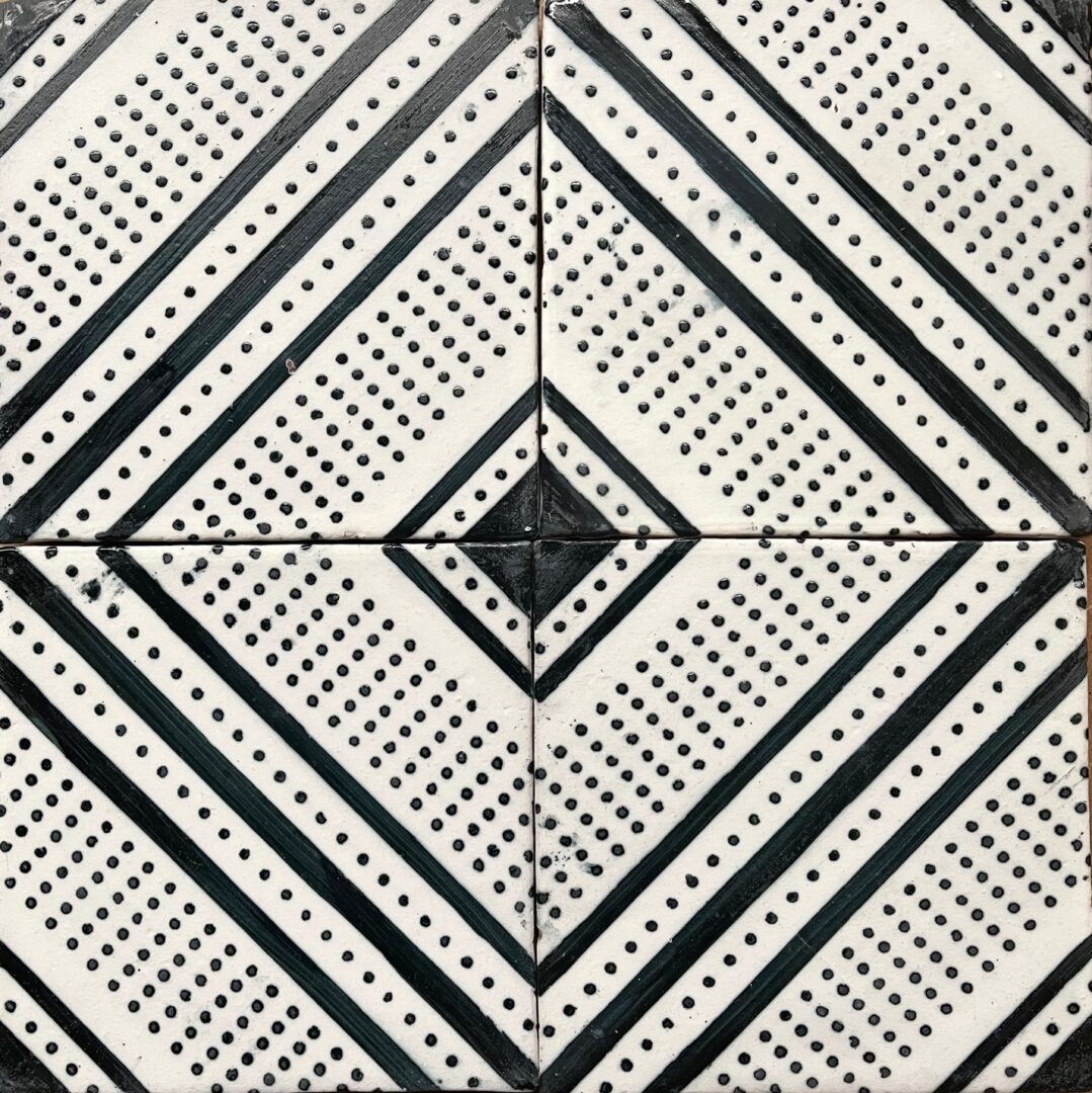 handmålat kakel med mönster av diagonala sträck och prickar i svart på vit bakgrund