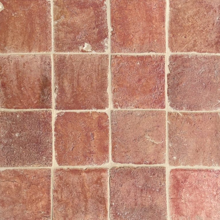 närbild av ett glaserat tegelgolv med röd/rosa nyanser som skapar en livfull atmosfär.