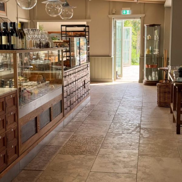 Stort café med en köpmannabänk i trä, inrett med antikbehandlad kalksten för en rustik känsla.