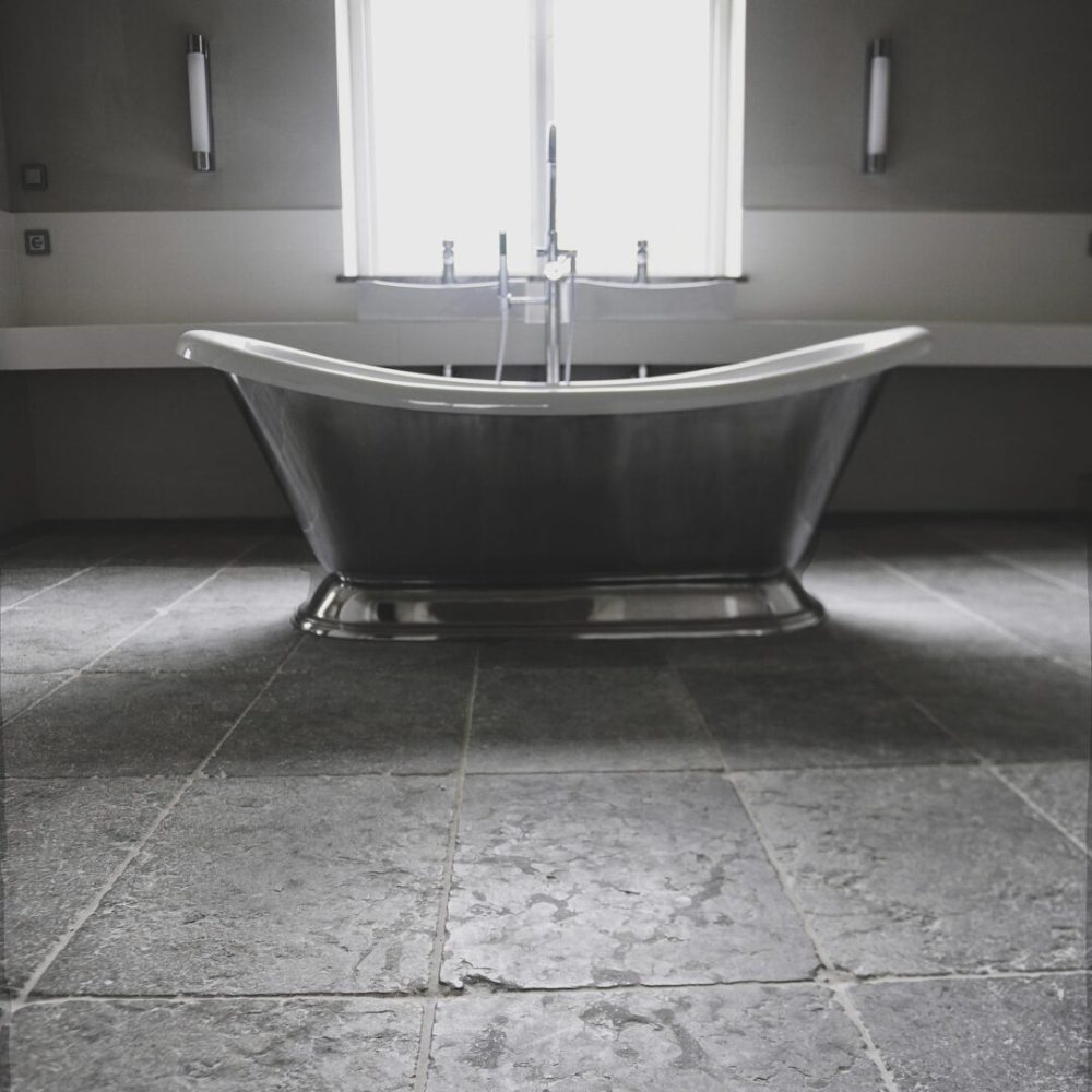 badrum med rustik grå tumlad kalksten på golvet