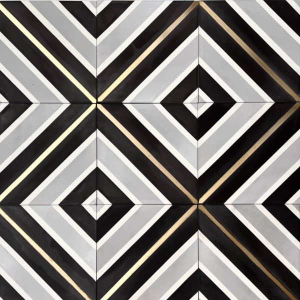 mönstrat cementgolv i grått, svart och vitt med inlägg av mässing