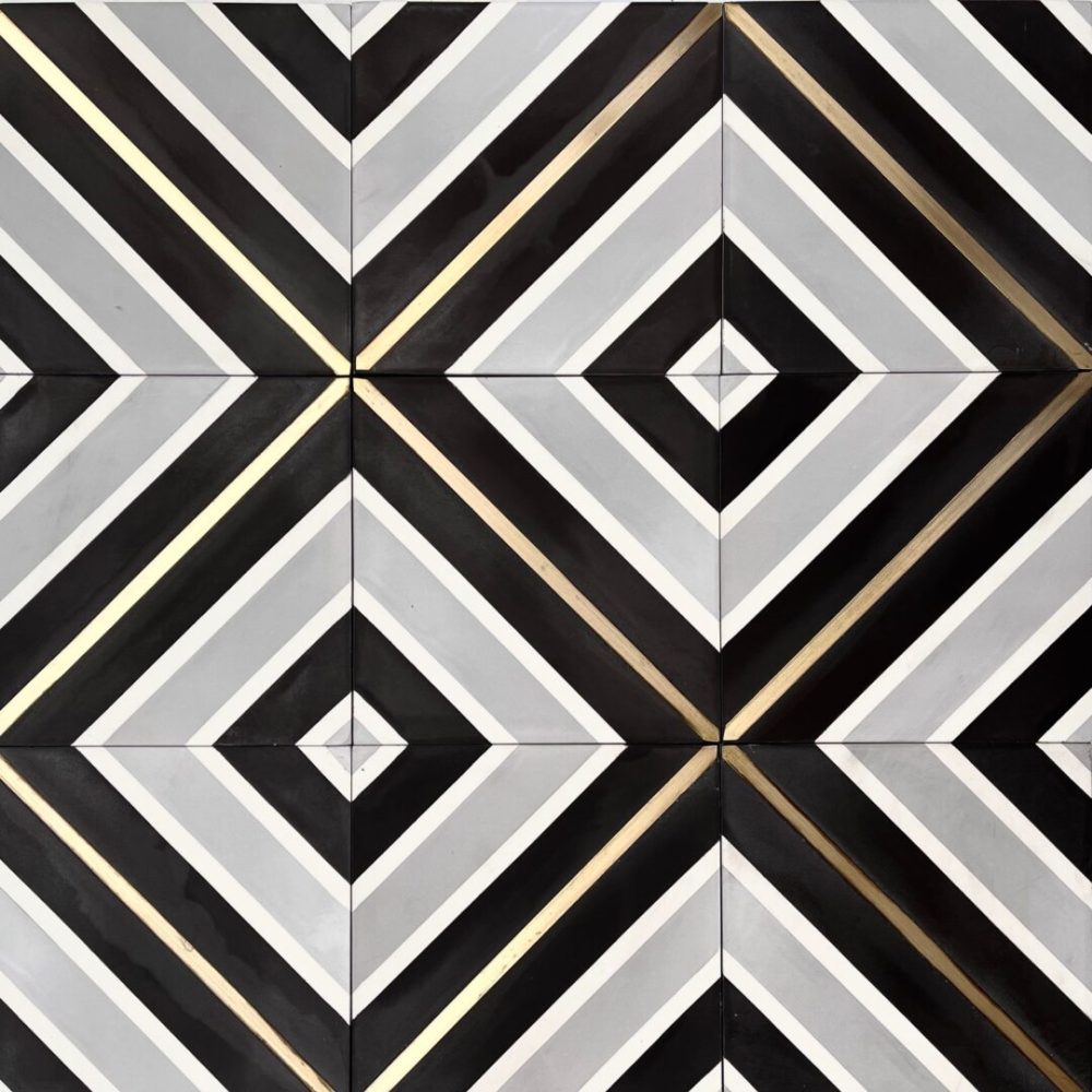 mönstrat cementgolv i grått, svart och vitt med inlägg av mässing