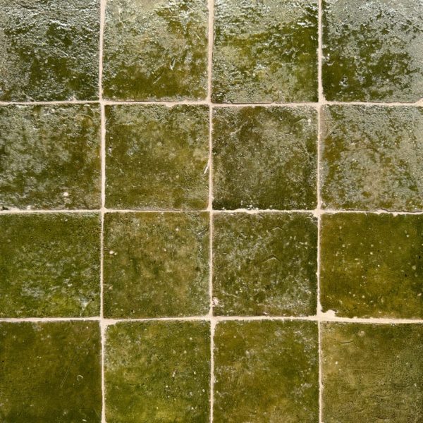 närbild av ett glaserat tegelgolv med nyanser i grönt som skapar en livfull atmosfär.