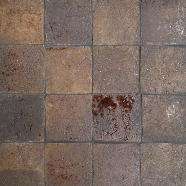 närbild av ett glaserat tegelgolv med nyanser i brunt som skapar en livfull atmosfär.