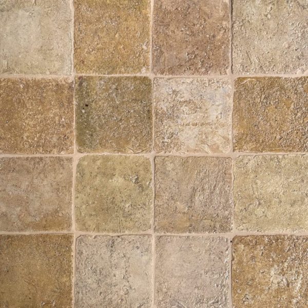 närbild av ett glaserat tegelgolv med rosa och beiga nyanser som skapar en livfull atmosfär.