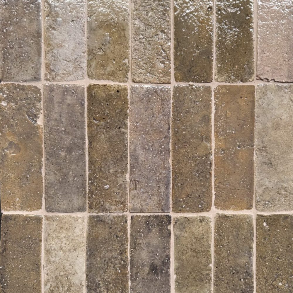 närbild av ett glaserat tegelgolv med nyanser i beige, brunt och lila som skapar en livfull atmosfär.