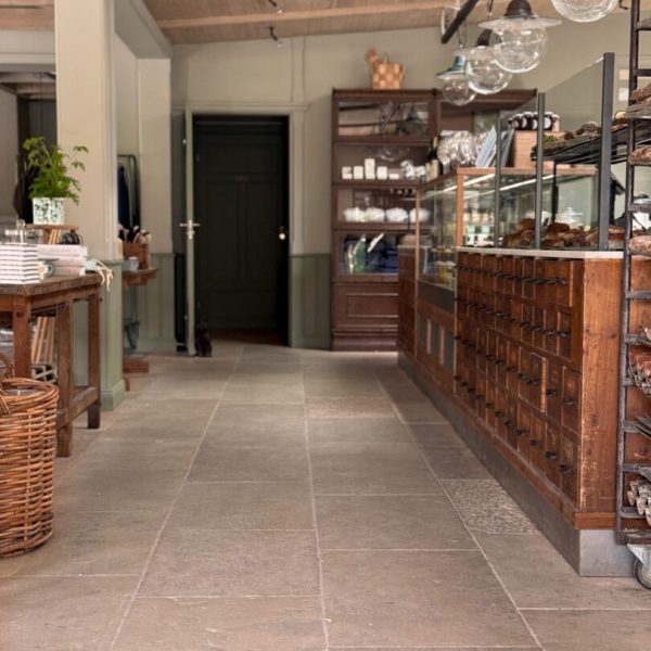 Stort café med en köpmannabänk och ett stort träbord, inrett med antikbehandlad kalksten för en rustik känsla.