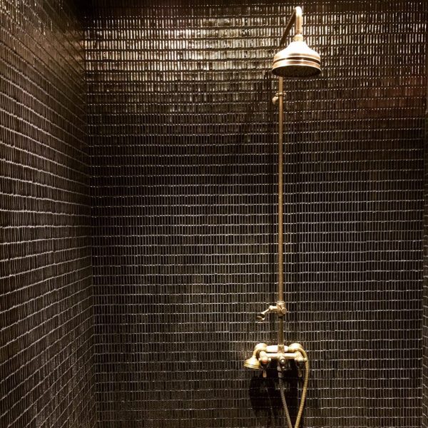 dusch med antikguldig keramikmosaik på väggarna