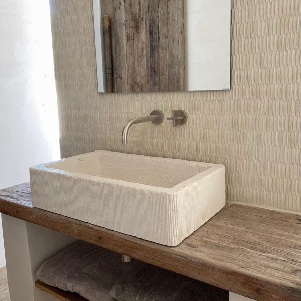 badrum med antikvit keramikmosaik i form av spetsiga ovaler på väggen bakom handfatet i sten