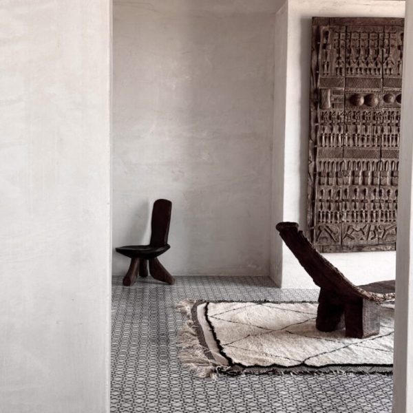 Ett rum med en rustik trästol, en träbänk och en marmormoasik som skapar en varm och inbjudande atmosfär.