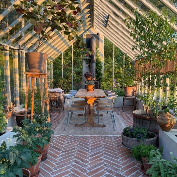 Växthus med matplats och rött tegel i fiskbensmönster på golvet